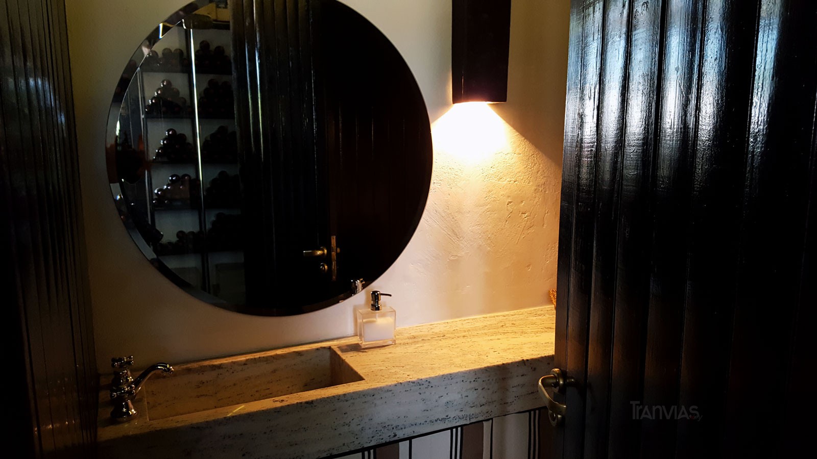 un baño pequeño pero a tono con el resto, en el espejo el reflejo de los vinos en pasillo