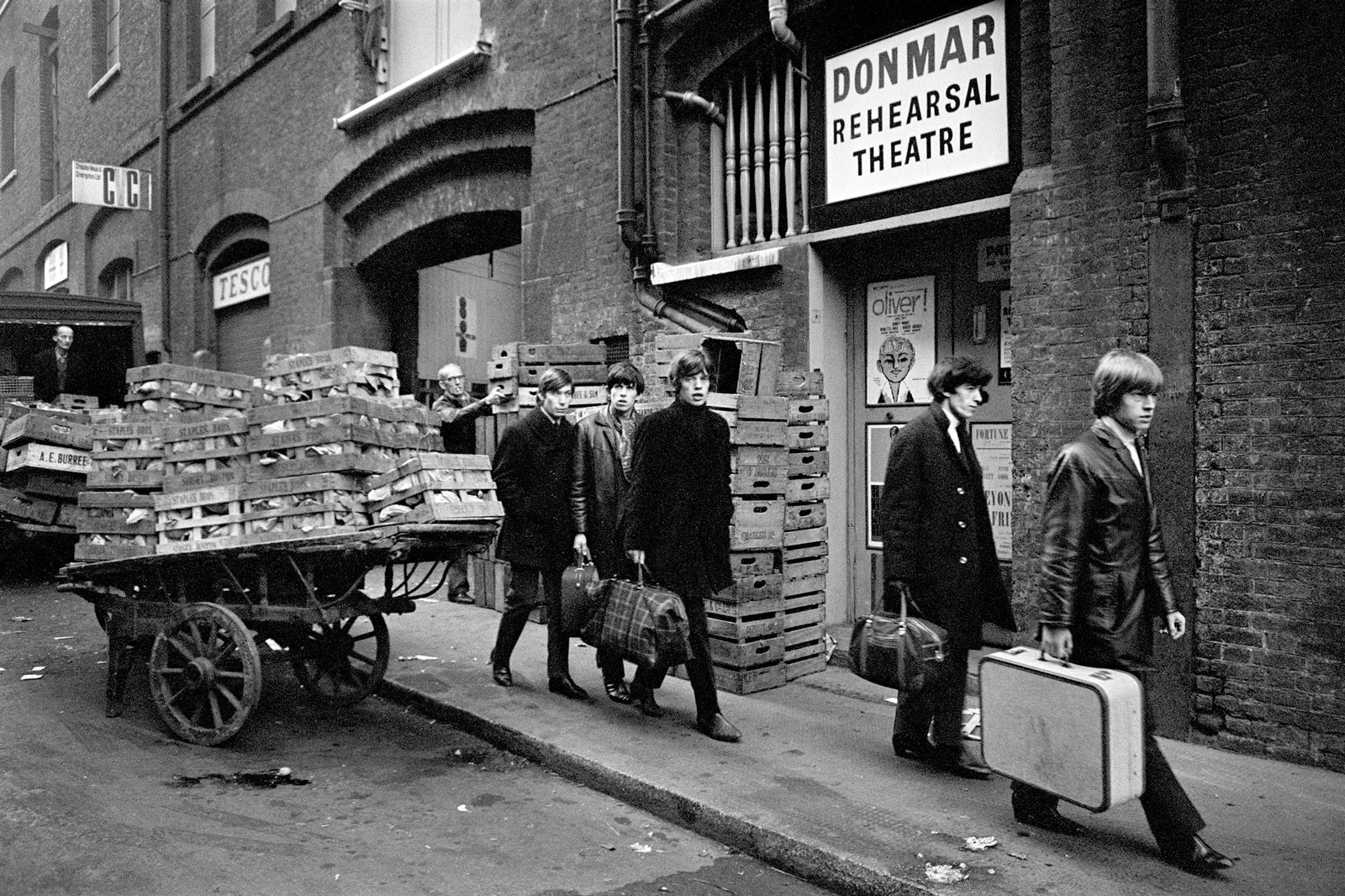 Los Stones caminando por un barrio popular, maletas en mano para salir de gira.